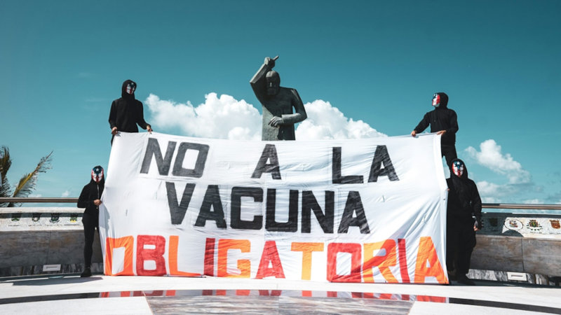 Activistas colocando una manta contra las vacunas